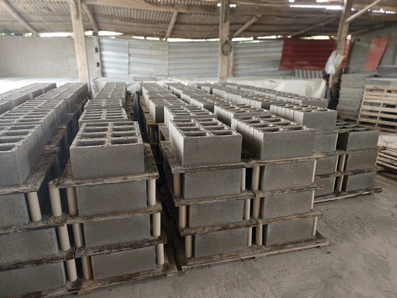 Blocos de concreto organizados em fileiras sobre suportes dentro de um galpão.